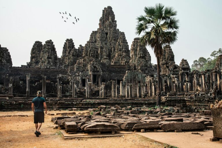 Traveler exploring the ancient Bayon Temple at Angkor Thom, Cambodia, surrounded by stunning architecture.