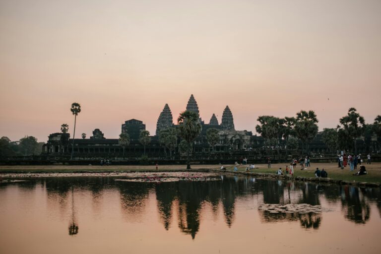 Beautiful sunset view of Angkor Wat with temple reflection in the lake and people enjoying the scenery.